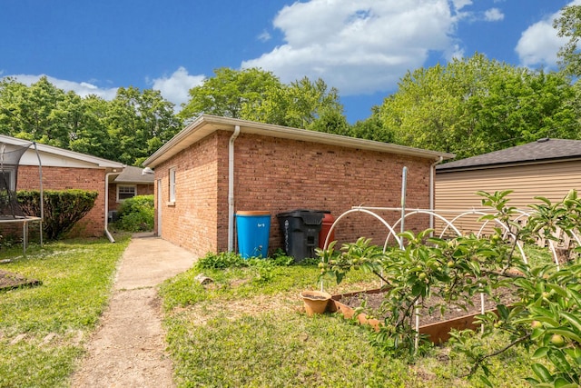 2417 Lyons St, Evanston, IL 60201 - view of property exterior featuring a garden, brick siding, a yard, and a trampoline
