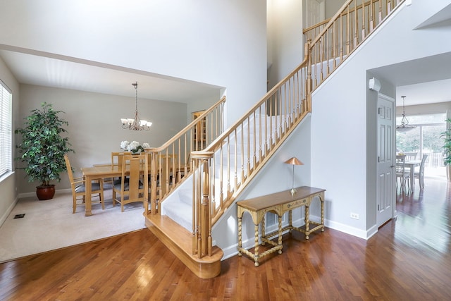 606 Ebony Dr, Oswego, IL 60543 - staircase with a chandelier, wood finished floors, and a towering ceiling