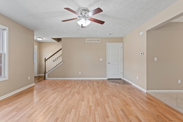 1610 Belclare Rd Unit 0, Normal, IL 61761 - empty room with a textured ceiling, a ceiling fan, stairway, and light wood-style floors