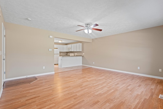 1610 Belclare Rd Unit 0, Normal, IL 61761 - unfurnished living room featuring a textured ceiling, a ceiling fan, and light wood-type flooring