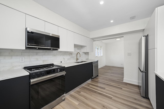 16030 University Ave, South Holland, IL 60473 - kitchen featuring appliances with stainless steel finishes, light countertops, tasteful backsplash, white cabinetry, and light wood-style floors