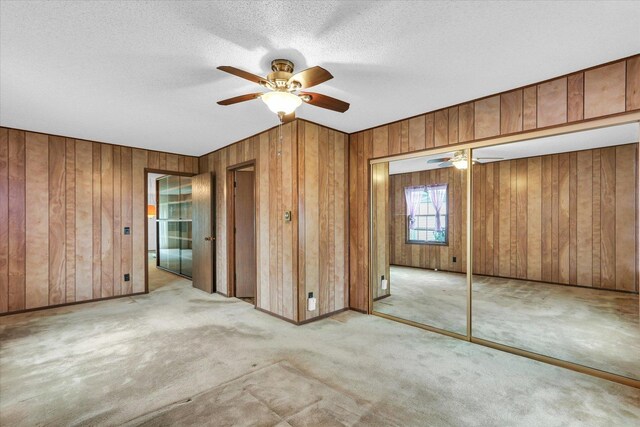907 E Glenview Dr, Tuscola, IL 61953 - unfurnished bedroom with wood walls, carpet floors, a closet, a ceiling fan, and a textured ceiling
