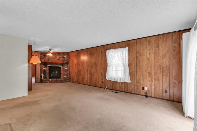 907 E Glenview Dr, Tuscola, IL 61953 - unfurnished living room featuring carpet flooring, a ceiling fan, wooden walls, a fireplace, and a textured ceiling