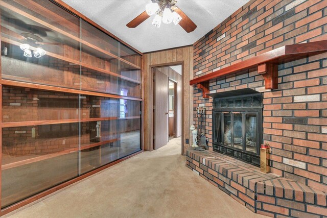 907 E Glenview Dr, Tuscola, IL 61953 - unfurnished living room with wood walls, a fireplace, carpet, a ceiling fan, and a textured ceiling