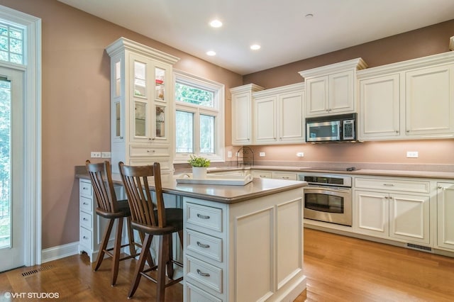 706 French Way Unit 2, Mount Prospect, IL 60056 - kitchen with appliances with stainless steel finishes, light wood-style flooring, recessed lighting, a breakfast bar, and white cabinetry