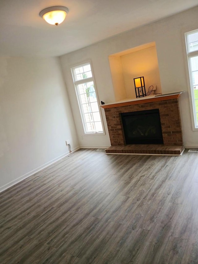 313 Manning Dr, Dekalb, IL 60115 - unfurnished living room featuring a brick fireplace, wood finished floors, and plenty of natural light
