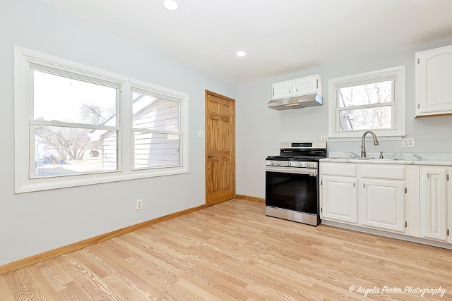 208 W Nippersink Rd, Round Lake, IL 60073 - kitchen featuring stainless steel range with gas stovetop, under cabinet range hood, light wood finished floors, white cabinets, and light countertops