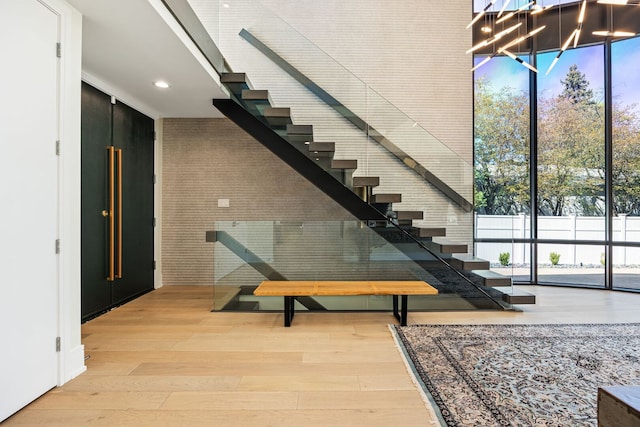 2110 Pfingsten Rd, Northbrook, IL 60062 - stairs featuring a wall of windows, wood finished floors, plenty of natural light, a high ceiling, and recessed lighting