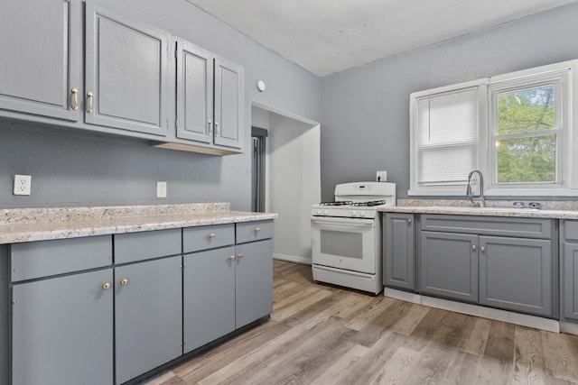 1121 Blaisdell St, Rockford, IL 61101 - kitchen with white range with gas cooktop, gray cabinets, and light wood-type flooring