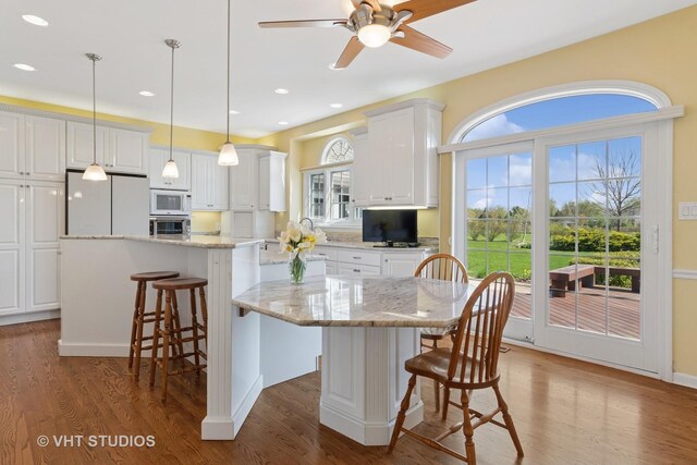 10603 Royal Porthcawl Dr, Naperville, IL 60564 - kitchen with white appliances, a center island, white cabinetry, a breakfast bar, and recessed lighting