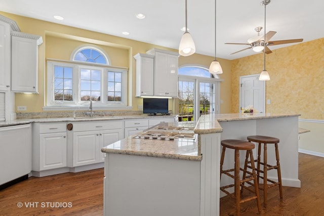 10603 Royal Porthcawl Dr, Naperville, IL 60564 - kitchen featuring white dishwasher, white cabinets, a center island, wood finished floors, and stovetop