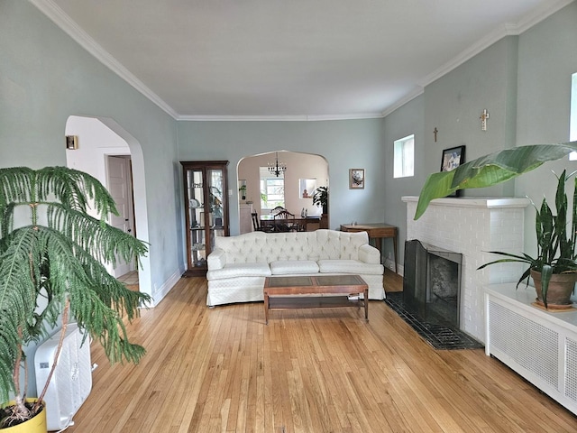 6515 N Maplewood Ave, Chicago, IL 60645 - living room with arched walkways, light wood finished floors, crown molding, radiator, and a fireplace
