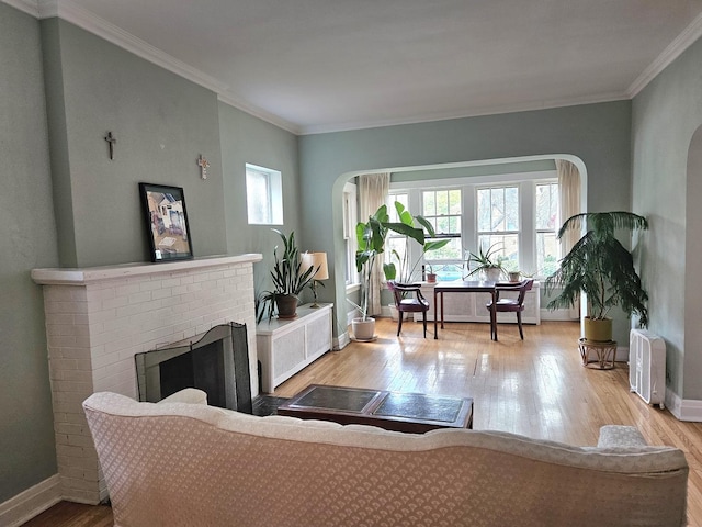 6515 N Maplewood Ave, Chicago, IL 60645 - living room with radiator, wood finished floors, a brick fireplace, crown molding, and arched walkways