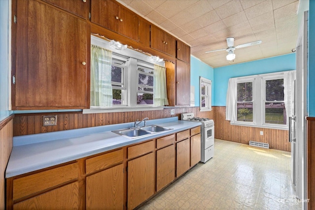 613 Jackson St, Aurora, IL 60505 - kitchen with white range with gas stovetop, light countertops, ceiling fan, a wainscoted wall, and wood walls