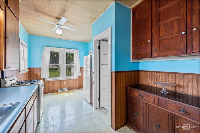 613 Jackson St, Aurora, IL 60505 - kitchen featuring freestanding refrigerator, white gas range oven, wainscoting, wooden walls, and ceiling fan