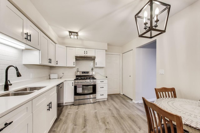 206 Country Ln, Des Plaines, IL 60016 - kitchen with appliances with stainless steel finishes, under cabinet range hood, decorative backsplash, and a chandelier