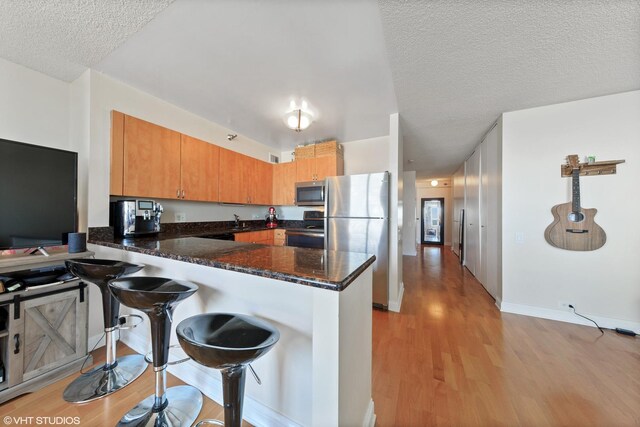 474 N Lake Shore Dr Unit 2801, Chicago, IL 60611 - kitchen with stainless steel appliances, a peninsula, light wood finished floors, a textured ceiling, and a breakfast bar