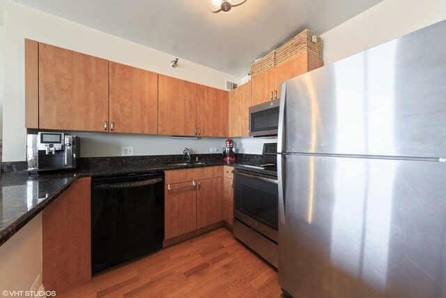 474 N Lake Shore Dr Unit 2801, Chicago, IL 60611 - kitchen featuring appliances with stainless steel finishes, light wood-style floors, dark stone counters, and brown cabinetry