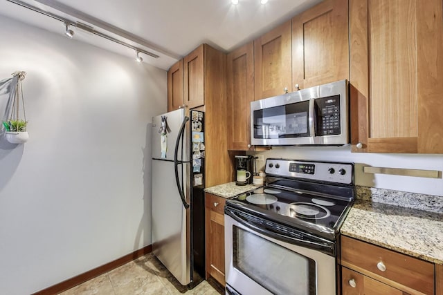 3033 N Sheridan Rd Unit 602, Chicago, IL 60657 - kitchen with stainless steel appliances, brown cabinetry, light stone counters, and track lighting