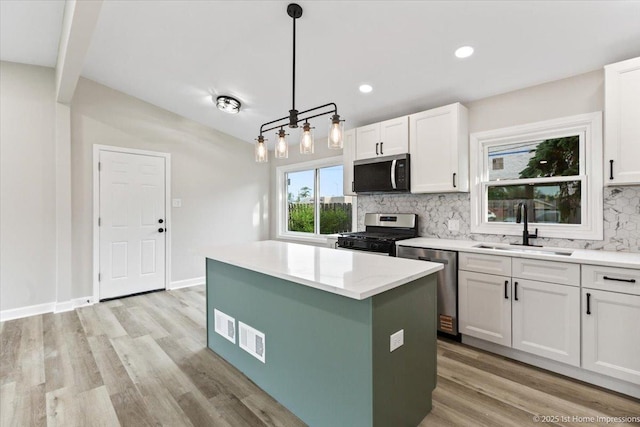 16211 Joyce Cir, South Holland, IL 60473 - kitchen featuring stainless steel appliances, decorative backsplash, a kitchen island, white cabinetry, and light wood finished floors