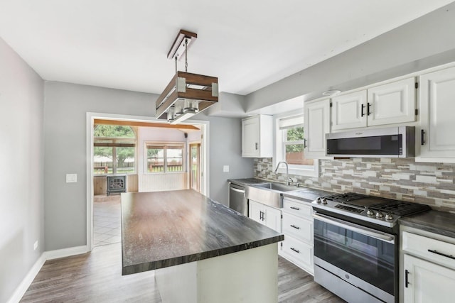 1888 Irene Rd, Sandwich, IL 60548 - kitchen with appliances with stainless steel finishes, dark countertops, decorative backsplash, white cabinets, and light wood-style flooring
