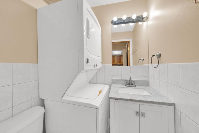 5848 W 76th Pl N Unit 203, Burbank, IL 60459 - bathroom featuring tile walls, estacked washer and dryer, vanity, and a wainscoted wall