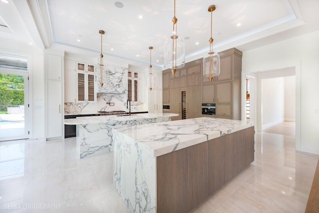 219 Lincoln Dr, Glencoe, IL 60022 - kitchen featuring a spacious island, a tray ceiling, oven, light stone countertops, and recessed lighting