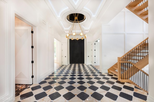 219 Lincoln Dr, Glencoe, IL 60022 - entrance foyer featuring coffered ceiling, stairs, a chandelier, crown molding, and a decorative wall
