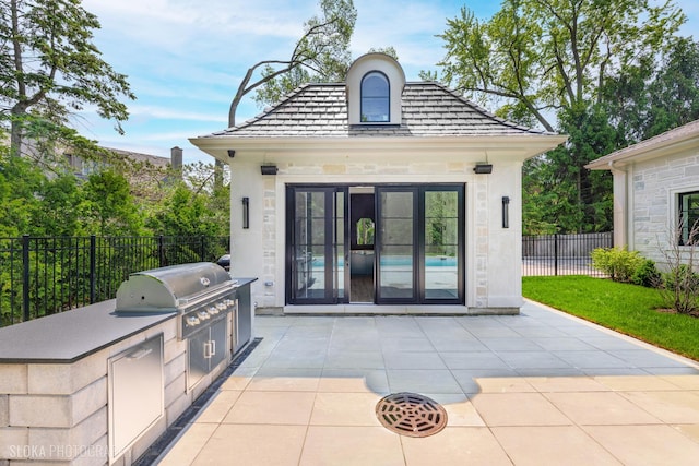 219 Lincoln Dr, Glencoe, IL 60022 - rear view of house with an outdoor kitchen, stone siding, an outbuilding, and a patio area