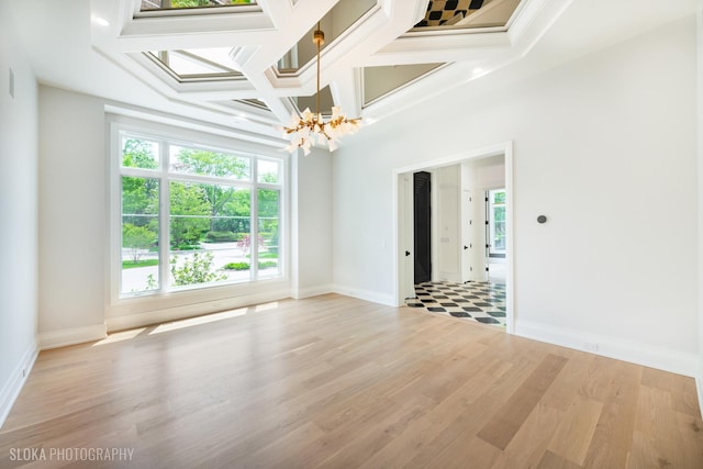 219 Lincoln Dr, Glencoe, IL 60022 - empty room with a chandelier, coffered ceiling, light wood-style flooring, and crown molding