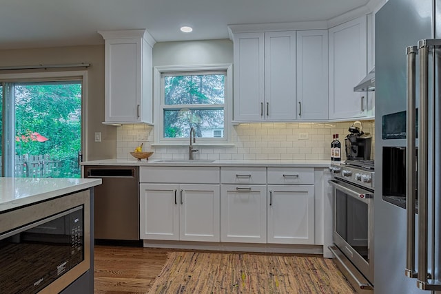 962 Thompson Blvd, Buffalo Grove, IL 60089 - kitchen featuring stainless steel appliances, under cabinet range hood, white cabinetry, backsplash, and light wood-type flooring