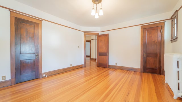 531 E Joliet St, Crown Point, IN 46307 - unfurnished bedroom with light wood-style floors, radiator, and a chandelier