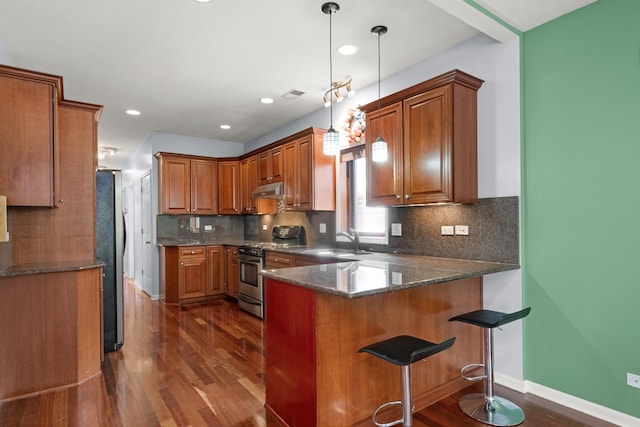 1031 N Mozart St Unit 2, Chicago, IL 60622 - kitchen with stainless steel appliances, dark wood finished floors, a peninsula, under cabinet range hood, and brown cabinets