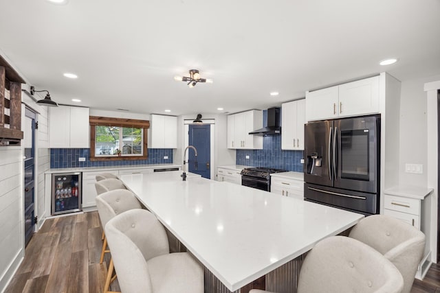 16430 S 89th Ave, Orland Park, IL 60462 - kitchen featuring stainless steel refrigerator with ice dispenser, wine cooler, wall chimney exhaust hood, black gas range, and a breakfast bar area