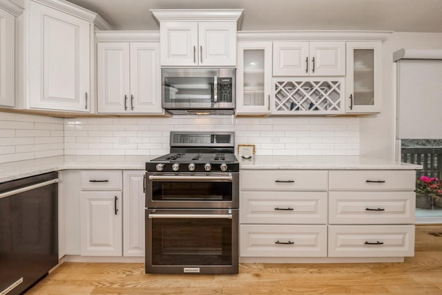 835 W 37th St Unit A, Chicago, IL 60609 - kitchen featuring appliances with stainless steel finishes, light stone counters, glass insert cabinets, and decorative backsplash