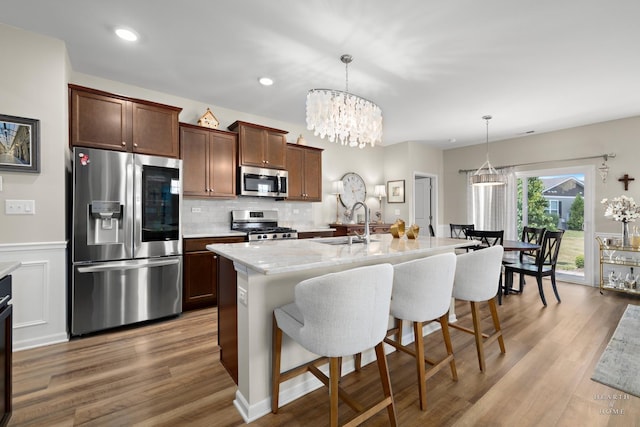 1106 Crestview Ln, Pingree Grove, IL 60140 - kitchen with appliances with stainless steel finishes, a kitchen bar, wood finished floors, backsplash, and a chandelier