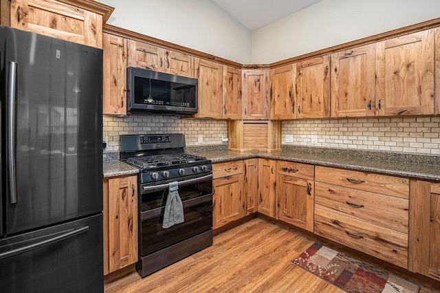 3872 Stadium St, Portage, IN 46368 - kitchen with black appliances, light wood-type flooring, backsplash, brown cabinets, and vaulted ceiling