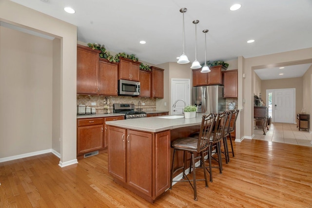 739 Pleasant Dr, Shorewood, IL 60404 - kitchen featuring appliances with stainless steel finishes, brown cabinetry, light wood finished floors, backsplash, and a kitchen breakfast bar