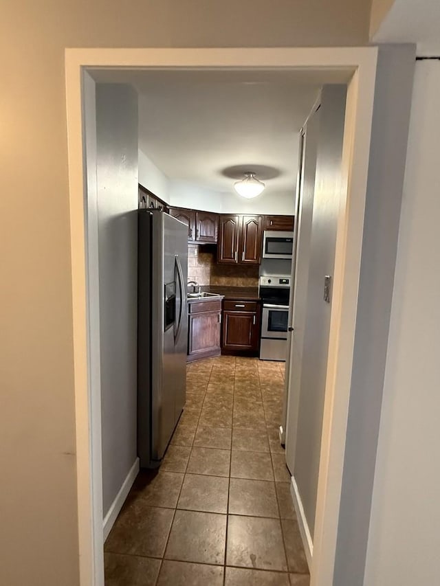 6033 N Sheridan Rd Unit 11L, Chicago, IL 60660 - kitchen featuring stainless steel appliances, backsplash, dark brown cabinetry, tile patterned flooring, and dark countertops