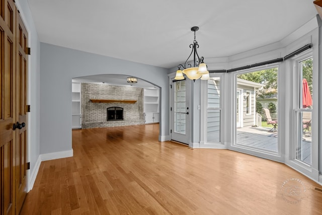 342 Dilorenzo Dr, Naperville, IL 60565 - unfurnished dining area featuring light wood-type flooring, arched walkways, a fireplace, and a chandelier