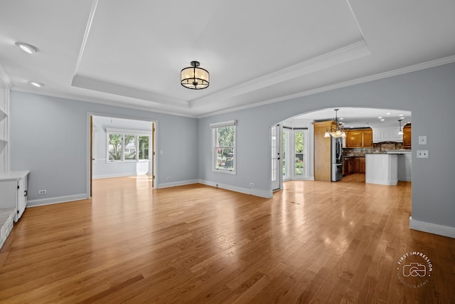 342 Dilorenzo Dr, Naperville, IL 60565 - unfurnished living room featuring a chandelier, arched walkways, a raised ceiling, plenty of natural light, and crown molding
