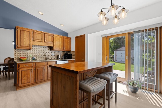 5555 Raspberry Trl, Rockford, IL 61114 - kitchen with light wood-style floors, a chandelier, vaulted ceiling, backsplash, and dishwashing machine