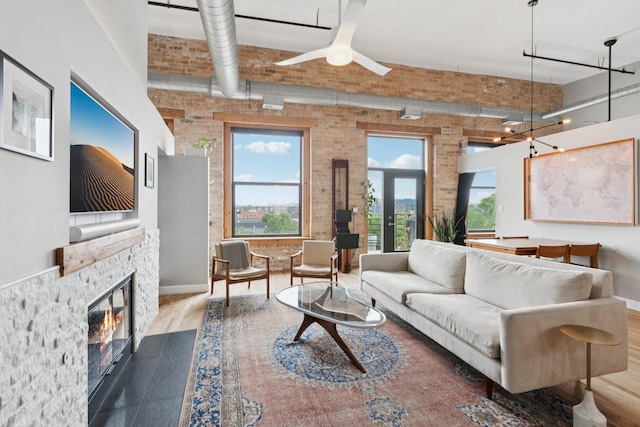 2511 W Moffat St Unit 501, Chicago, IL 60647 - living room with brick wall, ceiling fan, a stone fireplace, a towering ceiling, and wood finished floors