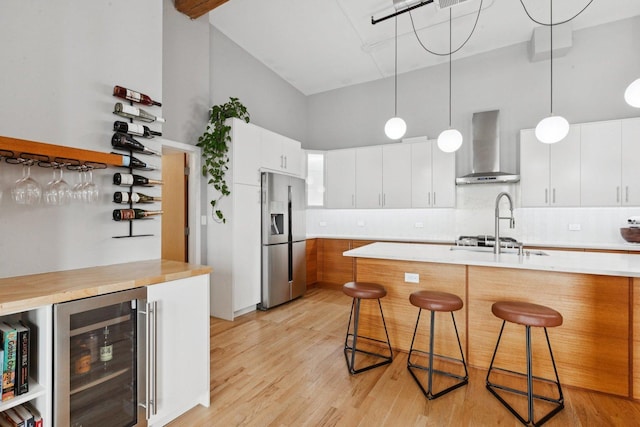 2511 W Moffat St Unit 501, Chicago, IL 60647 - kitchen with wall chimney range hood, stainless steel refrigerator with ice dispenser, wine cooler, a kitchen bar, and light countertops