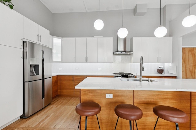 2511 W Moffat St Unit 501, Chicago, IL 60647 - kitchen featuring stainless steel fridge with ice dispenser, wall chimney range hood, a kitchen bar, light wood-style floors, and pendant lighting