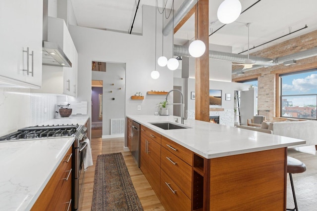 2511 W Moffat St Unit 501, Chicago, IL 60647 - kitchen featuring stainless steel appliances, wall chimney exhaust hood, modern cabinets, brown cabinetry, and a high ceiling