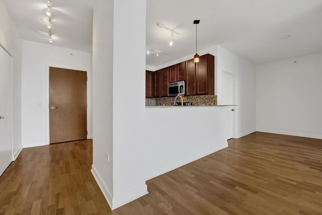 100 E 14th St Unit 2007, Chicago, IL 60605 - kitchen with stainless steel microwave, rail lighting, wood finished floors, decorative backsplash, and decorative light fixtures