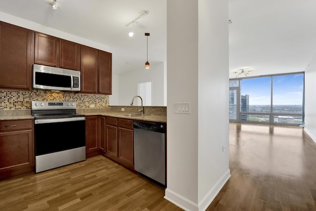 100 E 14th St Unit 2007, Chicago, IL 60605 - kitchen featuring appliances with stainless steel finishes, tasteful backsplash, wood finished floors, track lighting, and expansive windows