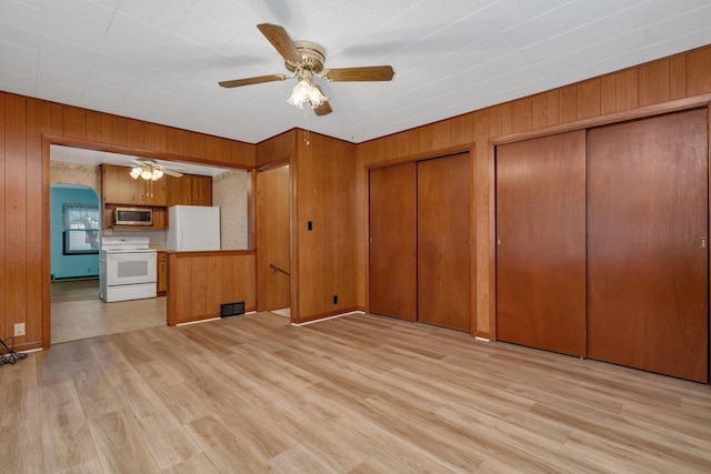 505 Douglas St, Morris, IL 60450 - unfurnished living room featuring ceiling fan, wooden walls, light wood-style floors, and arched walkways