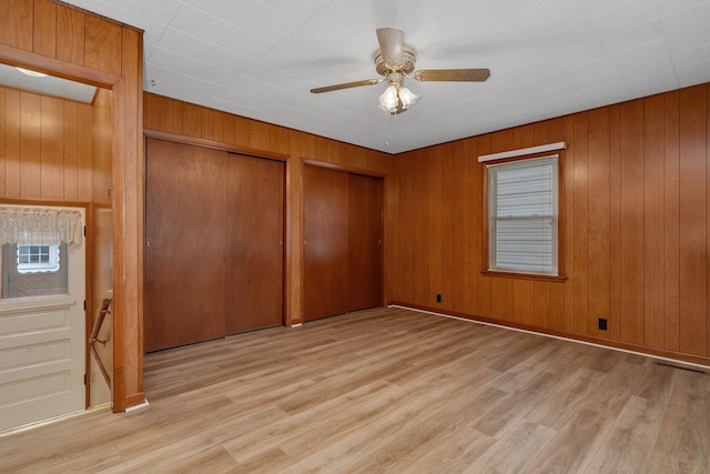 505 Douglas St, Morris, IL 60450 - unfurnished bedroom featuring multiple closets, light wood finished floors, wooden walls, and a ceiling fan